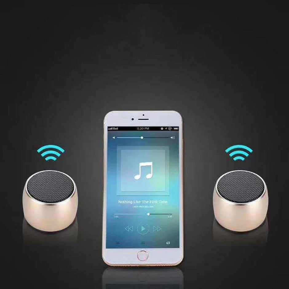 A smartphone playing music sits between two HeadphoneHeat.Com Portable Mini Bluetooth Speakers, each showing a blue wireless icon, against a black background for high-quality sound.