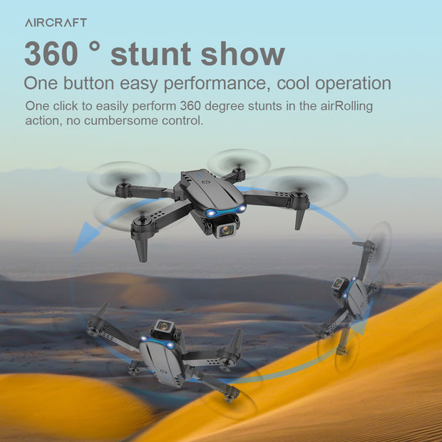 A K3pro Drone E99 Folding by Dropshipman performs 360° flips over sands. Text highlights its "360° stunt show" and easy one-button aerial stunts, while blue arrows emphasize the portable quadcopter’s flipping motion.