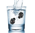A glass of water with two FLIPSTYLEZLLC T11 Wireless Bluetooth Headset 5.0 Earbuds submerged, while water is poured in, causing splashes and bubbles.