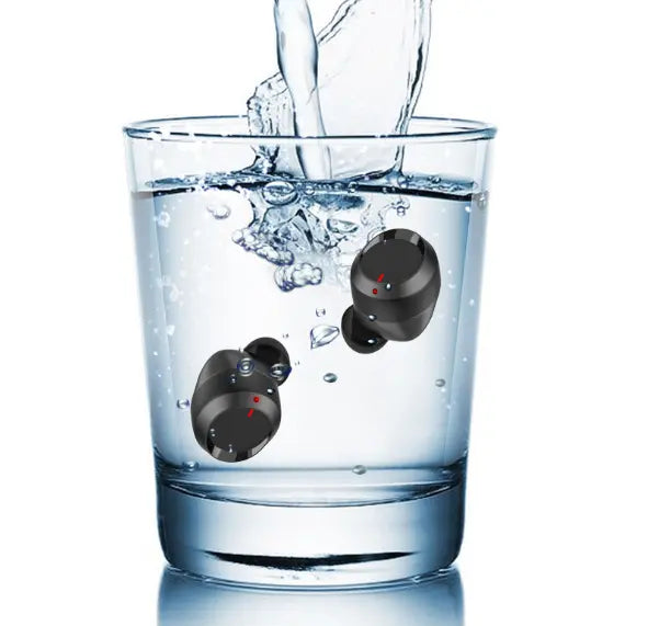 A glass of water with two FLIPSTYLEZLLC T11 Wireless Bluetooth Headset 5.0 Earbuds submerged, while water is poured in, causing splashes and bubbles.