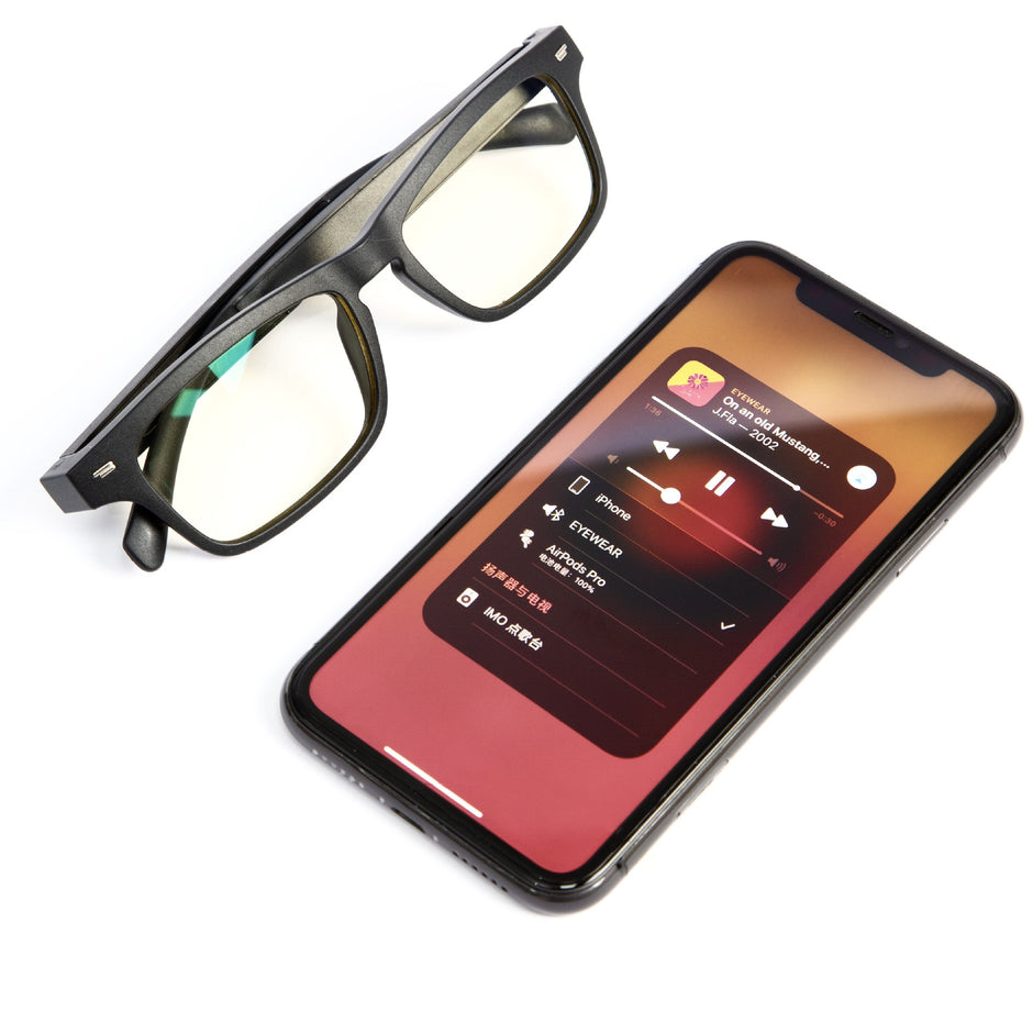 A pair of Dropshipman Smart Sunglass Headphones rests beside a smartphone showing a music player screen with album art, song details, and playback controls.