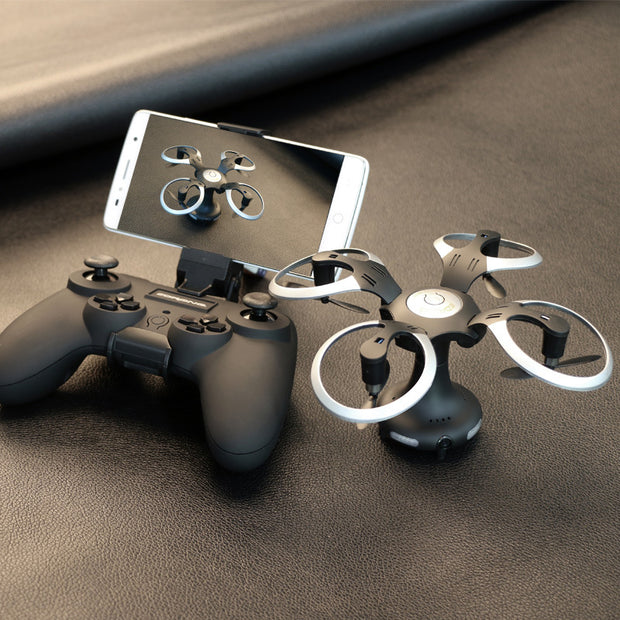 The Dropshipman High-definition Aerial Photography of Drones, in black and silver, sits with its controller and a smartphone streaming a live HD feed—creating a sleek, portable setup on a dark textured surface.