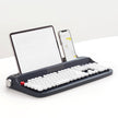 The Dropshipman Tablet Phone Wireless Bluetooth Typewriter features retro round white keys and built-in slots to hold your tablet and smartphone upright, displaying text and images as you type. This stylish wireless keyboard rests on a white surface.