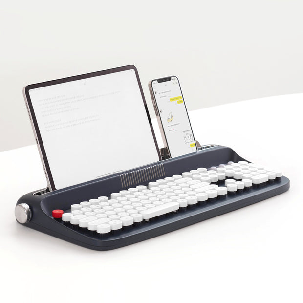 The Dropshipman Tablet Phone Wireless Bluetooth Typewriter features retro round white keys and built-in slots to hold your tablet and smartphone upright, displaying text and images as you type. This stylish wireless keyboard rests on a white surface.