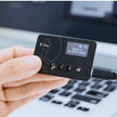 A person's hand is holding a compact, rectangular ImKey Pro Crypto Hardware Wallet with a screen displaying the text 