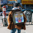 Man standing on city corner with LED backpack 