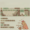 Introducing the HeadphoneHeat Capi Bara Mechanical Keyboard, featuring an ergonomic design with brown and green gradient keys adorned with icons like leaves and mushrooms. Some keys display a bear enjoying noodles, while the same bear illustration decorates the bottom right of this wireless gem.