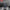 HeadphoneHeat choice HYUNDAI HY-Y16 AI translator OWS Wireless Bluetooth v5.4 earphones rest in their case next to a smartphone displaying a chat conversation. The backdrop showcases a reflective, liquid-like surface, with the text above stating, 