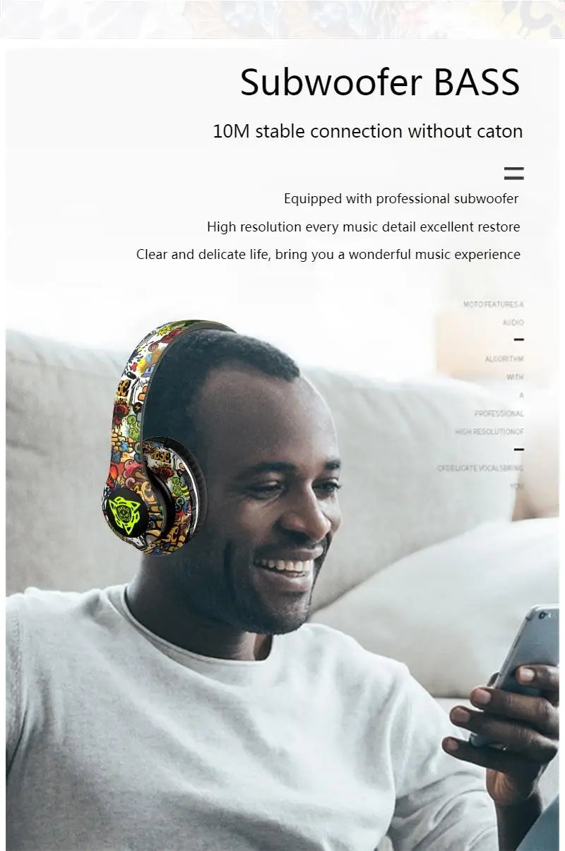 A man is smiling while wearing the vibrant Newmsnr Graffiti Foldable Wireless Bluetooth Headphones by HeadphoneHeat. He is sitting on a couch, with text above him stating 