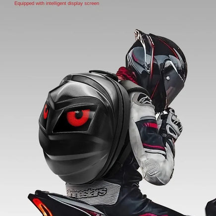 A motorcyclist in a sleek helmet and racing suit embodies the Moto & Biker Style as they ride a motorcycle, sporting a black LED Turtle Shell Backpack by HeadphoneHeat. The backpack features an animated display of large, red cartoon eyes reminiscent of Vampirina. The minimalist backdrop is a plain, light gray.