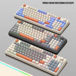 Three HeadphoneHeat K82 Mechanical Gaming Keyboards with vibrant, multi-colored keycaps are on display. Each of these wired keyboards boasts distinct color schemes, a volume knob, and USB connectivity. Text reads 