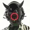 A person wears the HeadphoneHeat LED Lights Cyberpunk Full Face Mask with horn-like features and a red circular LED display on the visor, paired with a patterned black and white jacket against a plain white background.