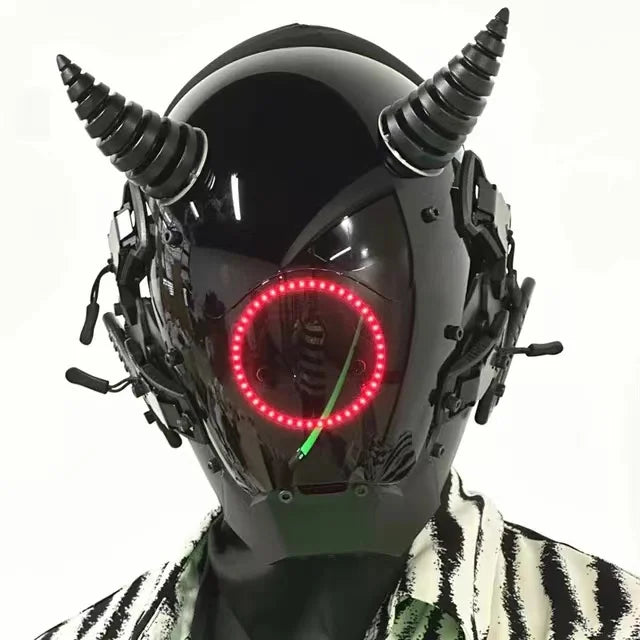 A person wears the HeadphoneHeat LED Lights Cyberpunk Full Face Mask with horn-like features and a red circular LED display on the visor, paired with a patterned black and white jacket against a plain white background.
