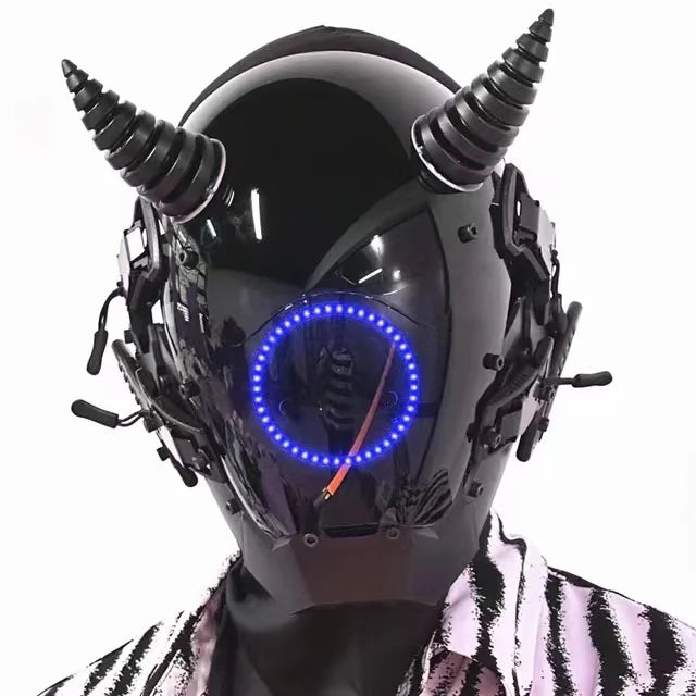 Wearing the HeadphoneHeat LED Lights Cyberpunk Full Face Mask, a sleek black helmet with conical horns and a glowing circle on the faceplate, paired with side mechanical details, perfectly complements a patterned garment for a modern vibe.