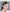 A person with long brown hair is wearing a white HeadphoneHeat Esports ZIXZEX Game Bluetooth TWS Earbud in their right ear. They are looking slightly to the left and touching their ear. The background is light gray, and the text 