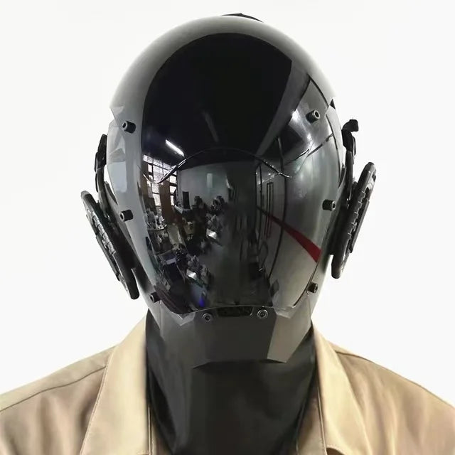 A person wearing a sleek, glossy black LED Lights Cyberpunk Full Face Mask by HeadphoneHeat. The visor reflects the surroundings, and the helmet, with LED lights and side attachments, flaunts a high collar for a modern cyberpunk look. The person is dressed in tan clothing.