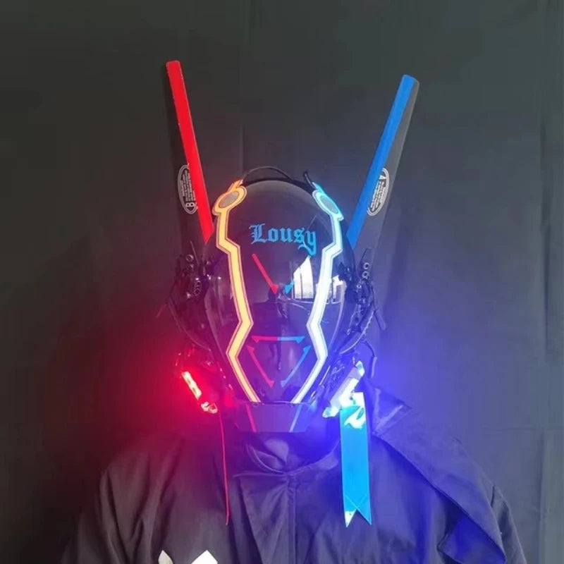 A person wears a HeadphoneHeat LED Lights Cyberpunk Full Face Mask with neon red and blue lights. The helmet features antenna-like extensions and a visor displaying "Lousy." They are dressed in dark attire against a matching dark backdrop.