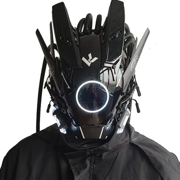 A person wears a HeadphoneHeat LED Lights Cyberpunk Full Face Mask, featuring a futuristic black design with angular details, mechanical accents, glowing white LEDs, and tubes for a high-tech look. They are dressed in dark attire.