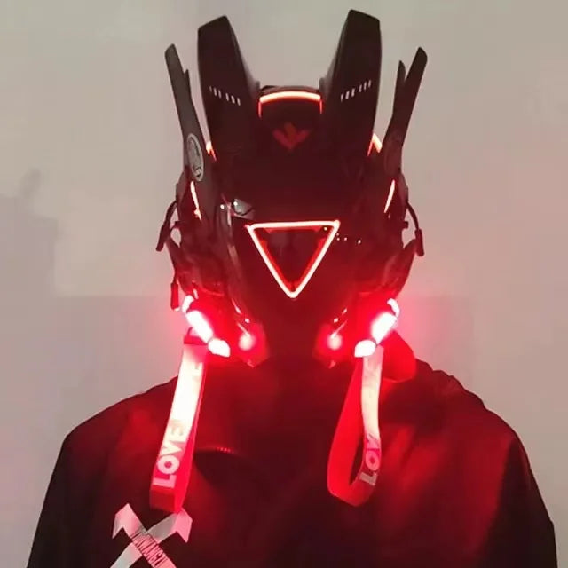 A person wears the HeadphoneHeat LED Lights Cyberpunk Full Face Mask with a red LED-lit triangular visor and ear-like protrusions. White 