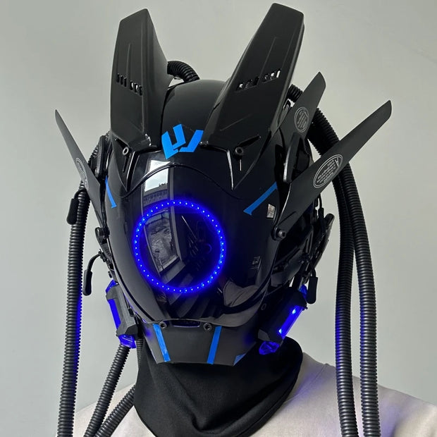 The HeadphoneHeat LED Lights Cyberpunk Full Face Masks feature angular designs, blue LED lighting with a front circular light ring, and electronic protrusions and tubing for a sci-fi robotic look.