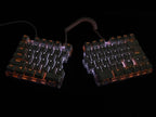 The DEBROGLIE LT78 by HeadphoneHeat is a split, ergonomic mechanical keyboard with Kailh switches and backlit keys on a sleek black background. It features customizable positioning with its coiled cable, and the softly glowing white keys add an elegant touch.