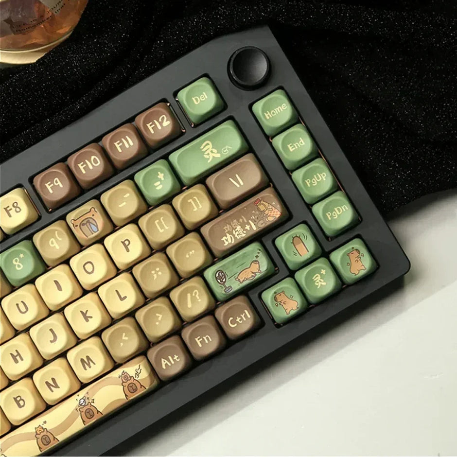 The Capi Bara Mechanical Keyboard by HeadphoneHeat features earthy-toned keycaps with symbols and illustrations, including animals and geometric designs. It offers an ergonomic design in green, brown, and beige on a black frame with seamless wireless technology.