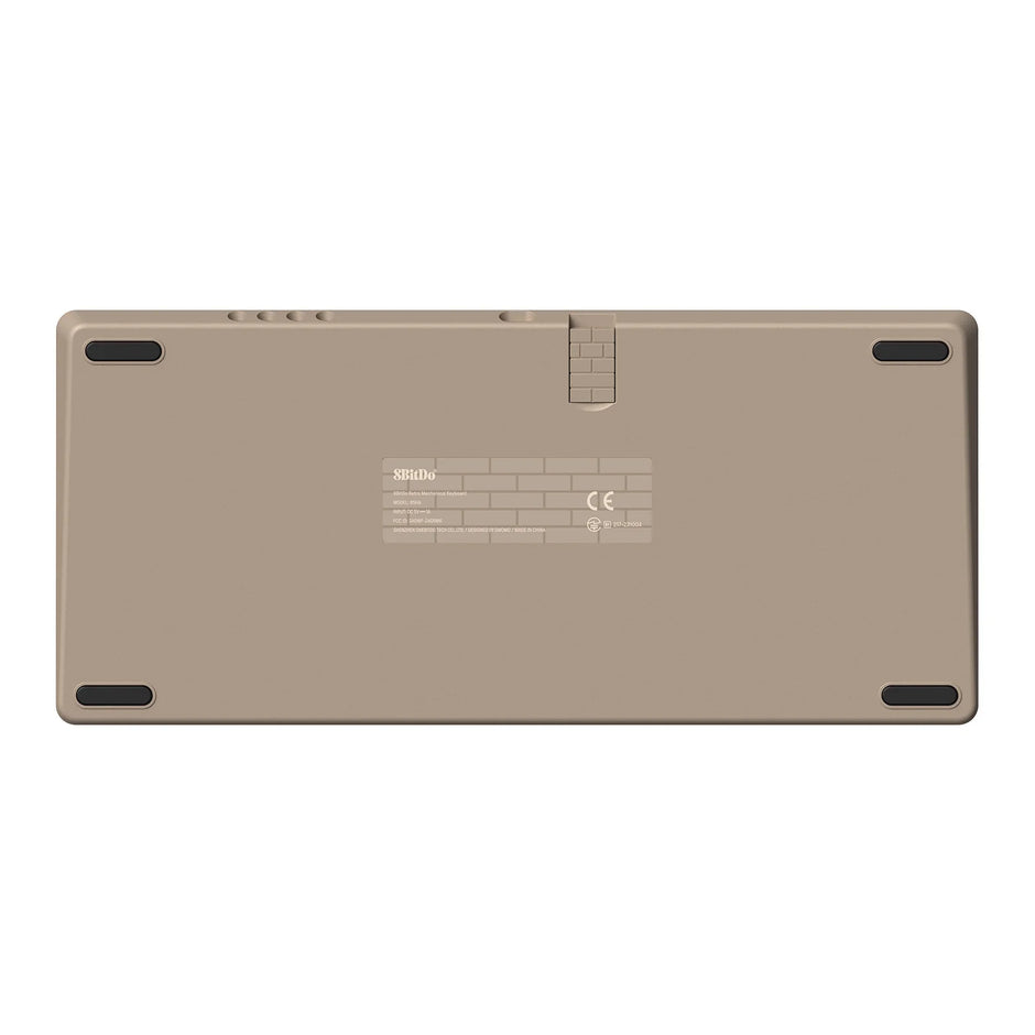 The image displays the back of a beige electronic device with rubber grips on the corners, reminiscent of an 8BitDo Retro Mechanical Keyboard design by HeadphoneHeat. It includes a label with text and symbols in the center and features a hinge-like detail at the top, enhancing its retro mechanical keyboard aesthetic.