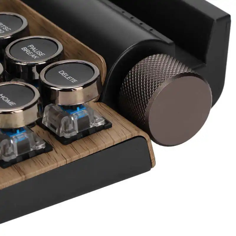 Close-up of HeadphoneHeat's Retro Typewriter Mechanical Keyboard corner featuring chrome-edged round keys and visible blue switches, with a large textured metallic knob on the right. The wood-texture background complements its seamless integration of Bluetooth 5.0 connectivity.