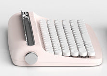 The Dropshipman Tablet Bluetooth Typewriter features a modern, pastel pink design with round white keys and a shiny silver knob. Shown from a side angle on a plain light background.