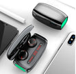 A pair of FLIPSTYLEZLLC T11 Wireless Bluetooth Headset 5.0 Earbuds in an open charging case with LED display rests on a white surface beside a smartphone, tablet, and another closed case.