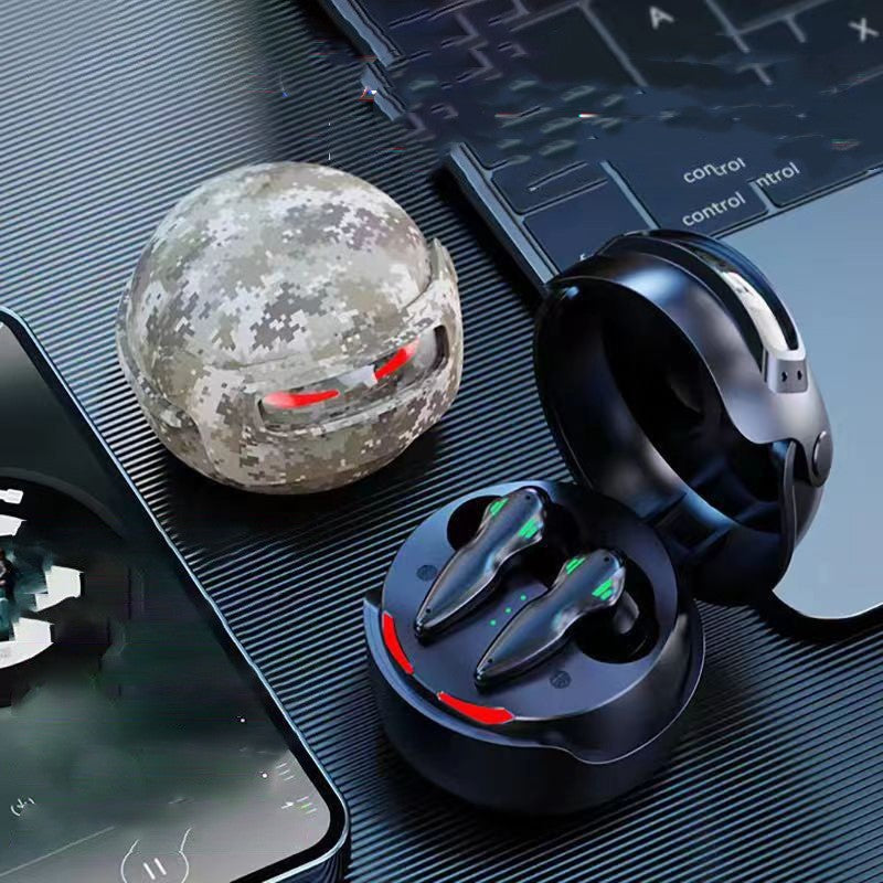 Two pairs of Dropshipman Fortipod Earbuds with Bluetooth 5.3 in spherical charging cases—one black, one digital camo—are displayed next to a smartphone and a laptop keyboard on a dark, textured surface.