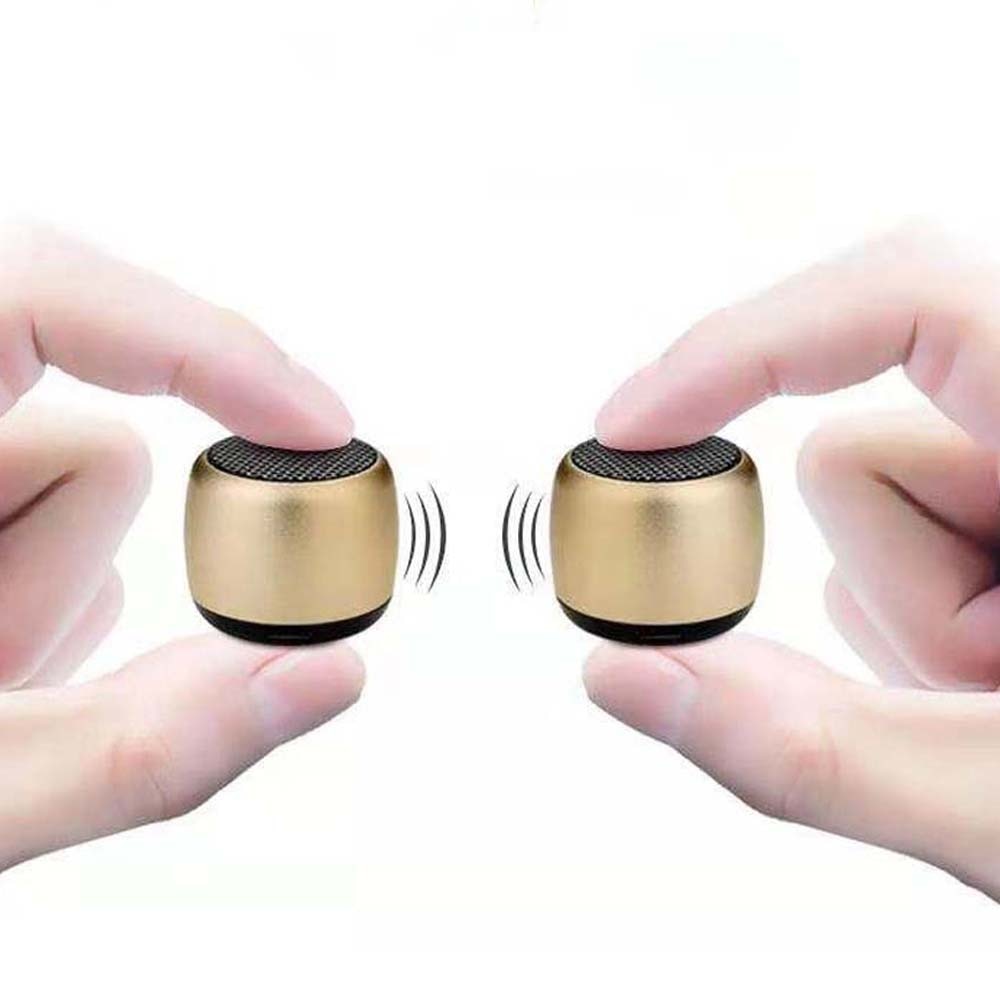 Two fingers on each side hold small, gold-colored Portable Mini Wireless Bluetooth Speakers from HeadphoneHeat.Com, facing each other. Sound wave symbols show enhanced sound quality against a plain white backdrop, highlighting their compact and durable design.