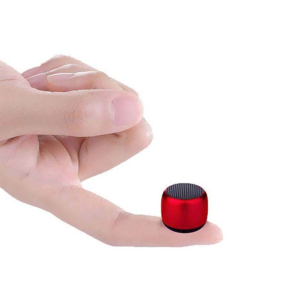 A red Portable Mini Wireless Bluetooth Speaker with Enhanced Sound Quality from HeadphoneHeat.Com is delicately balanced on a fingertip against a plain white background, promising high-quality sound wherever you go.